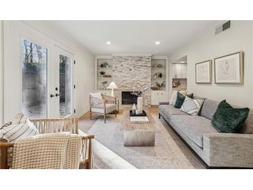 Bright living room features a stone fireplace, built-in shelving, and French doors leading to a patio at 54 Ivy Ne Pkwy, Atlanta, GA 30342