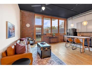 Open living area with exposed brick, hardwood floors, and large windows at 660 Glen Iris Ne Dr # 204, Atlanta, GA 30308