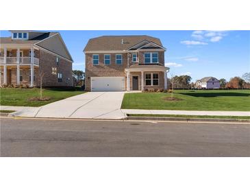 Two-story brick home with a large driveway and landscaped lawn at 245 Chiswick Loop, Stockbridge, GA 30281