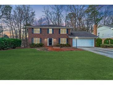 Charming two-story brick home featuring a well-manicured lawn and a two car garage at 5323 Lakesprings Dr, Dunwoody, GA 30338