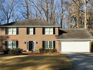 Brick two-story house with a white garage and landscaping at 5323 Lakesprings Dr, Dunwoody, GA 30338