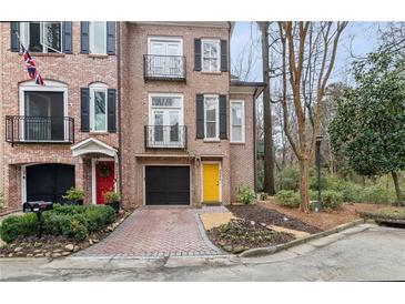 Charming brick townhome featuring black shutters, a yellow front door, and a well-manicured front yard at 3245 Buckhead Forest Ne Mews, Atlanta, GA 30305