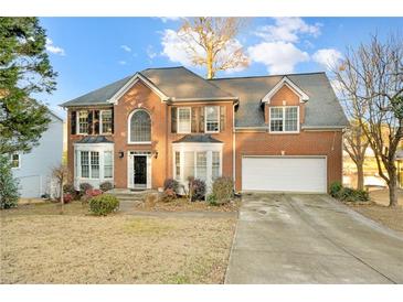 Brick two-story house with a large driveway and landscaped lawn at 2265 Wildwood Lake Dr, Suwanee, GA 30024