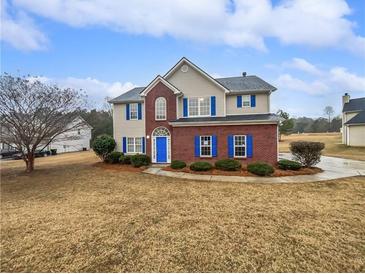 Two-story house with brick and siding, blue shutters, and a landscaped lawn at 7085 Magnolia Ln, Fairburn, GA 30213