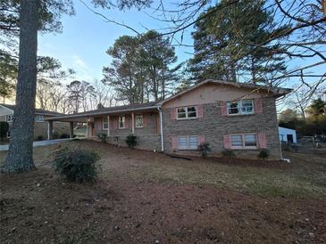 Brick ranch house with pink shutters, landscaped yard, and driveway at 5737 Lorraine Dr, Stone Mountain, GA 30087