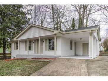 Charming white brick home featuring a covered front porch with classic columns and a matching carport at 6565 Bussell Way, Riverdale, GA 30274
