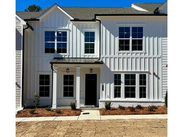 New construction townhome with white vertical siding, black trim, and manicured landscaping at 405 Nettle Ct, Woodstock, GA 30188