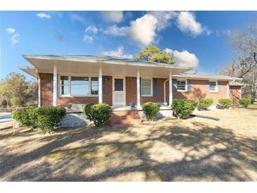 Brick ranch house with a covered porch and landscaped yard at 2555 Klondike Rd Sw, Conyers, GA 30094