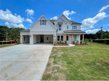 A beautiful, newly-built two-story home features light brick, white painted siding and a three car attached garage at 679 Crest Line Trl, Powder Springs, GA 30127
