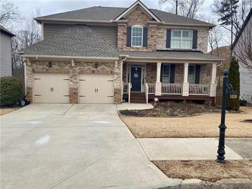 Charming two-story home features a brick and stone facade, covered porch, and a two-car garage at 1320 Newbridge Cir, Buford, GA 30519