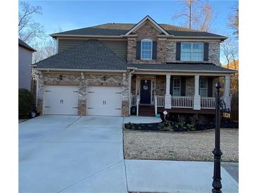 Charming two-story home featuring a two-car garage, brick and stone facade, and a welcoming front porch at 1320 Newbridge Cir, Buford, GA 30519