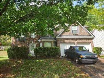 Brick two-story house with a two-car garage and landscaped lawn at 5789 Star Flower Dr, Ellenwood, GA 30294