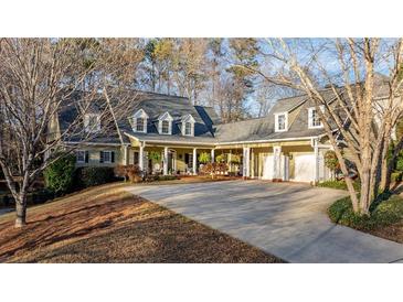 Inviting home featuring a long driveway, well-maintained landscaping, and a charming covered front porch at 4924 Red Cliff Ct, Powder Springs, GA 30127