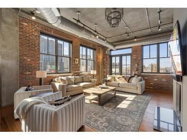 Bright living room with exposed brick, industrial-style ceiling, large windows, and comfortable seating at 3235 Roswell Ne Rd # 617, Atlanta, GA 30305