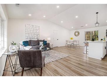 Open concept living room featuring modern decor, wood floors, and vaulted ceilings at 1428 Muirfield Dr, Stone Mountain, GA 30088