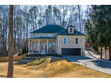 Two-story brick home with front porch and attached garage, nestled amongst mature trees at 1496 Sweet Bottom Sw Cir, Marietta, GA 30064