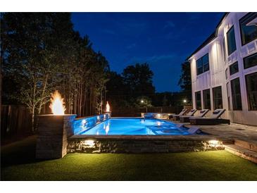 Stunning outdoor pool with adjacent lounge chairs, spa, and fire pit features at night at 100 Chateau Pl, Woodstock, GA 30188