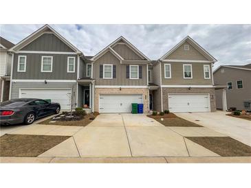 View of townhomes with driveways and garages, showcasing the building's exterior at 7540 Knoll Hollow Rd, Lithonia, GA 30058