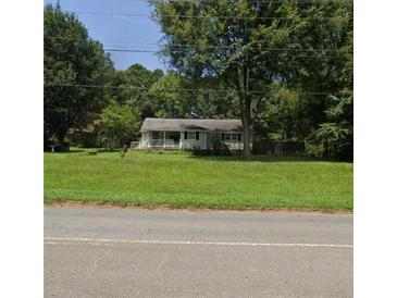 Charming single-story home with a covered front porch surrounded by mature trees and a spacious front lawn at 1381 Allgood Rd, Marietta, GA 30062