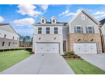 New townhome with a tandem two car garage, modern brick facade, and green lawn at 5707 Tillman Way, Powder Springs, GA 30127