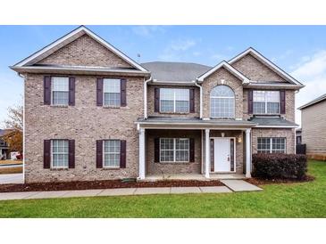 Brick two-story house with a large front yard and landscaping at 5010 Mundy Dr, Cumming, GA 30028