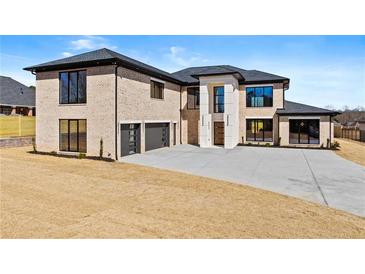 Stunning modern home featuring a brick facade, black trim, a spacious driveway, and a two-car garage at 2753 Camp Branch Rd, Buford, GA 30519