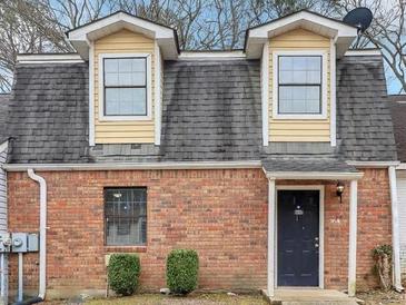 Charming brick townhome featuring a black front door, dormer windows, and mature landscaping at 8690 Ashley Way, Douglasville, GA 30134