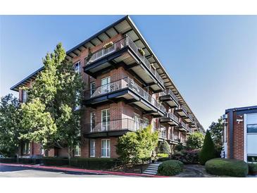 Modern brick apartment building with black metal balconies, surrounded by lush green landscaping and trees at 5200 Peachtree Rd # 3221, Chamblee, GA 30341
