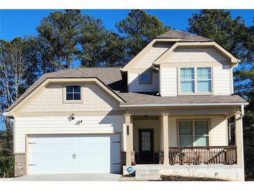 Two-story house with beige siding, white garage door, and a front porch at 2308 Hanover Woods Rd, Lithonia, GA 30058