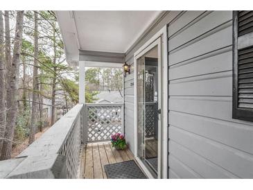 View of the balcony featuring gray wood siding, white railings, and sliding glass door at 204 Natchez Trce, Sandy Springs, GA 30350