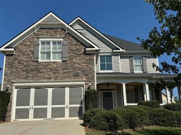 Two-story home with stone and siding accents, three-car garage, and landscaped yard at 4335 Silent Path, Cumming, GA 30028