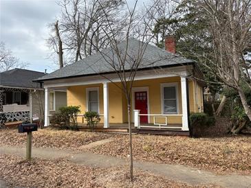 Charming yellow cottage with a red door, inviting front porch, and classic architectural details at 3033 Semmes St, Atlanta, GA 30344