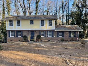 Two-story brick house with yellow accents, featuring a large front yard and mature trees at 1600 Whisperwood Trl, Stone Mountain, GA 30088