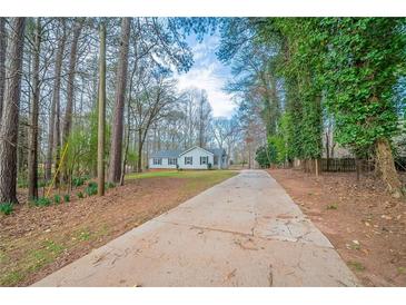 Charming single-story home features a long driveway surrounded by mature trees and a well-manicured lawn at 270 Merrydale Dr, Fayetteville, GA 30215