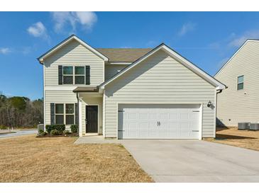 Charming two-story home with a two-car garage and well-maintained front yard with blue skies overhead at 7889 Winkman Dr, Fairburn, GA 30213