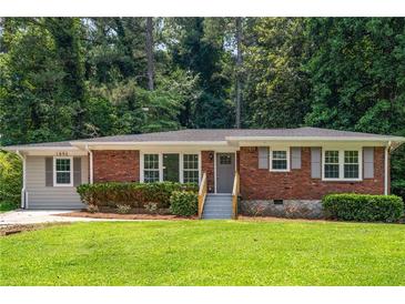 Charming brick home with a well-manicured lawn and gray painted siding at 1893 Windsor Sw Dr, Atlanta, GA 30311