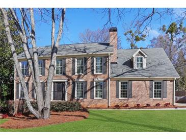 Charming two-story brick home with a well-manicured lawn and traditional architectural details at 6792 Hunters Trace Cir, Atlanta, GA 30328