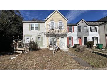 Charming townhome featuring a well-maintained lawn, colorful siding, and a welcoming entrance at 497 Prince Of Wales, Stone Mountain, GA 30083