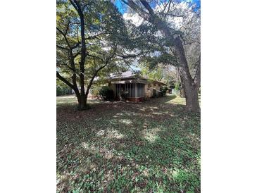 Charming home with a screened front porch, nestled among mature trees and lush ground cover at 5157 West St, Covington, GA 30014