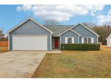 Charming single-story home with blue siding, attached garage, manicured landscaping, and inviting red front door at 642 Jenmarie Sw Dr, Mableton, GA 30126