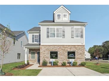 Charming two-story home with gray siding, brick facade, and inviting curb appeal on a sunny day at 2015 Wyndham Pl, Conyers, GA 30013