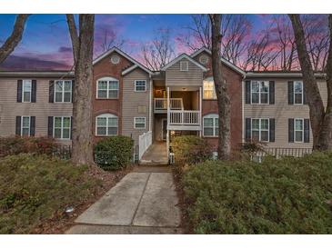 Inviting two-story condo with a mix of brick and siding, complemented by lush landscaping at dusk at 384 Teal Ct, Roswell, GA 30076