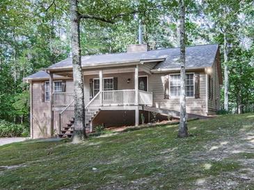 Charming home with a inviting front porch surrounded by mature trees on a sloped lawn at 4422 Fincher Rd, Canton, GA 30114
