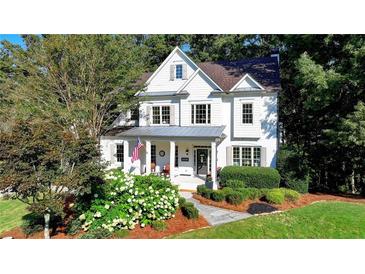 Charming two-story home featuring a well-manicured lawn, landscaped flower beds, and classic American-style architecture at 5760 Windjammer Pt, Cumming, GA 30041