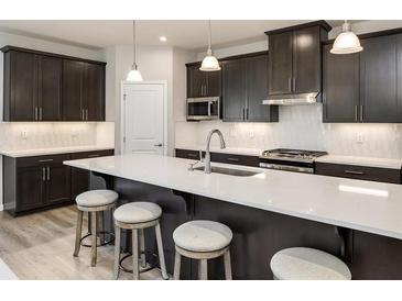 Bright kitchen features a large island with seating, modern appliances, and stylish dark brown cabinetry at 1141 Burlington Ct, Mcdonough, GA 30253