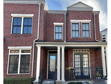 Charming brick townhouse featuring black-framed windows and a welcoming front porch with columns at 4666 Magnolia Commons, Dunwoody, GA 30338
