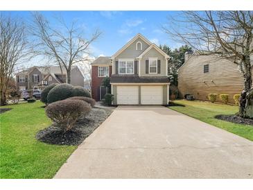 Charming home featuring a two-car garage, landscaped yard, and traditional architectural details at 2750 Dominion Walk Ln, Snellville, GA 30078