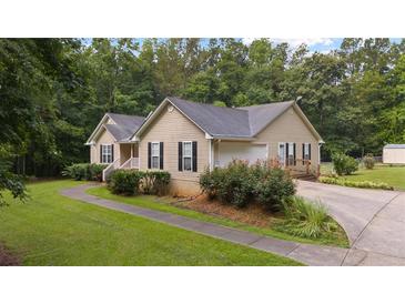 Charming single-story home features tan siding, black shutters, and an attached garage, nestled among lush trees at 4156 Holly Springs Rd, Rockmart, GA 30153