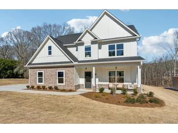 Charming two-story home with a stone facade, white siding, a covered porch, and a well-maintained lawn at 6035 Hendrix Rd, Cumming, GA 30040