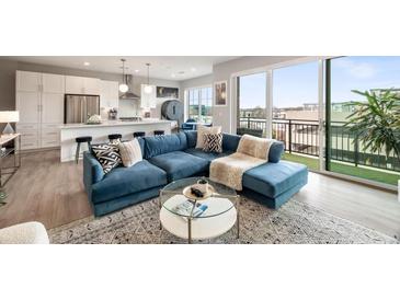 Bright living room with a blue sectional sofa, open to the kitchen and a balcony with black railing at 22 Airline Street Ne # 403, Atlanta, GA 30312